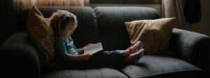 kid reading book on couch
