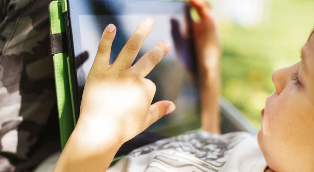 kid laying down using tablet